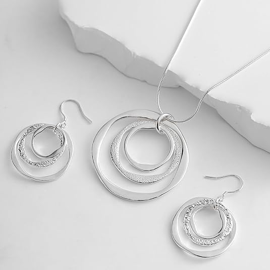 Silver jewelry set with necklace and earrings on a light background
